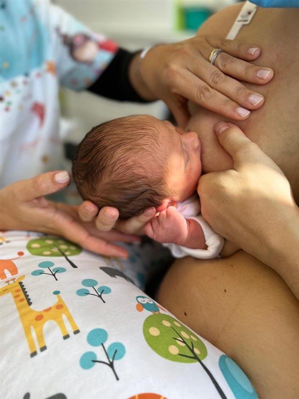 Mãe amamentando bebê recém-nascido durante visita do Home Care Pós Parto